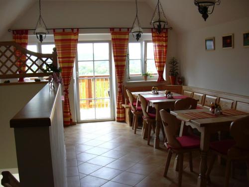 un comedor con mesas, sillas y ventanas en Weingut Gästezimmer Gruber, en Ehrenhausen