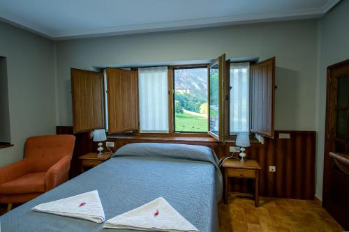 1 dormitorio con 1 cama, 1 silla y 1 ventana en La Casona de Rey, en Alvariza