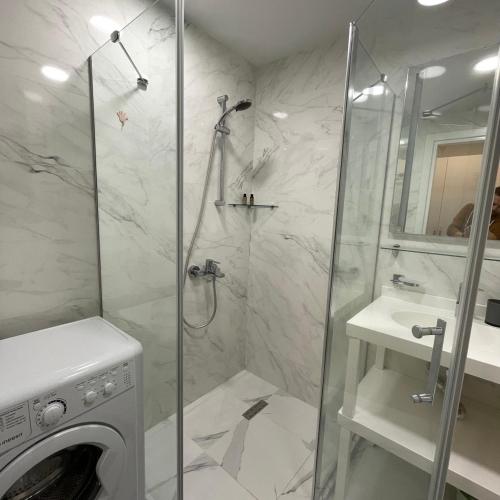 a bathroom with a shower and a washing machine at Real Beach Tower in Batumi