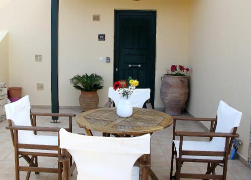 una mesa y sillas con un jarrón de flores. en Ninas Place, 5min On Foot From The Beach, en Panormos Rethymno