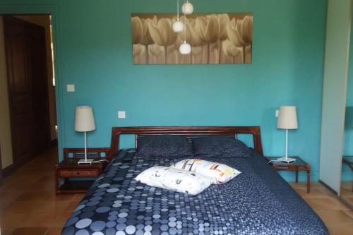 ein blaues Schlafzimmer mit einem Bett mit zwei Kissen darauf in der Unterkunft Villa de charme la Vinadière avec piscine privée et chauffée in Voutezac