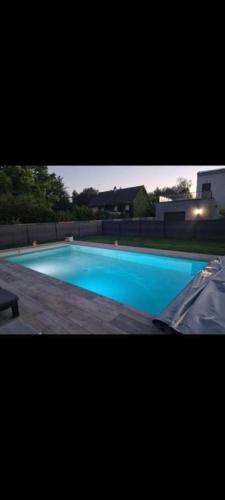 une grande piscine bleue avec un bâtiment en arrière-plan dans l'établissement Chambre n°2 dans logement - Chez Ana, à Changé