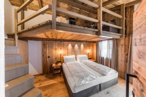 1 dormitorio con 1 cama elevada y paredes de madera en Rifugio Salei, en Canazei