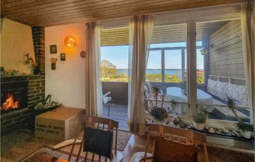 a living room with a fireplace and a large window at Nice Home In Bergastrand With Wifi in Berga Strand