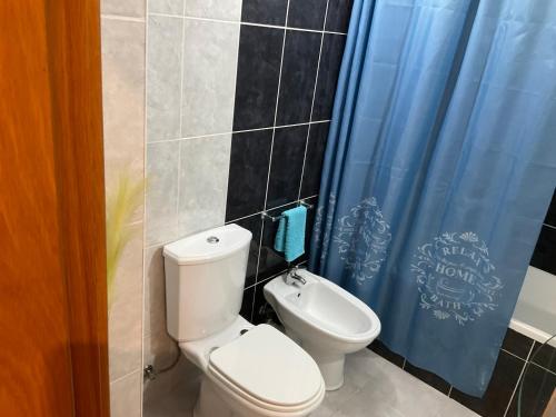 un bagno con un water e una tenda da doccia blu di Moniz Apartment a Caniço