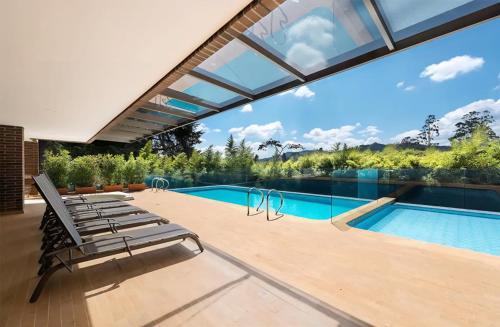 una piscina con tumbonas y una ventana grande en Apartment in countryside with hotel services, en Rionegro