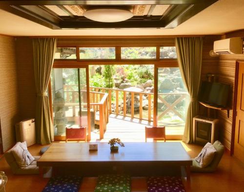 - un salon avec une table et une grande fenêtre dans l'établissement Garden House Umenoya Otaru, à Otaru