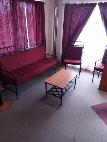 una sala de estar con muebles rojos y cortinas rojas. en Cabañas Aron, en San Fabián de Alico