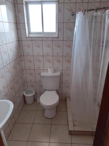 baño con aseo y lavabo y ventana en Cabañas Aron, en San Fabián de Alico