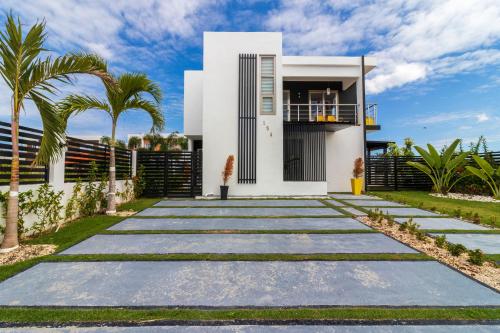 a white house with palm trees in front of it at Modern 4-BR Villa with Pool in Punta Cana Residential Area in Punta Cana