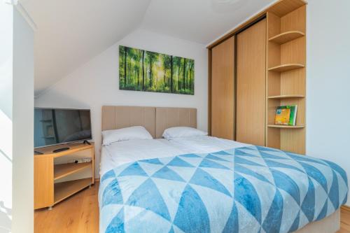 a bedroom with a bed and a flat screen tv at Meadow House Łąkowa 5 Mikoszewo in Mikoszewo