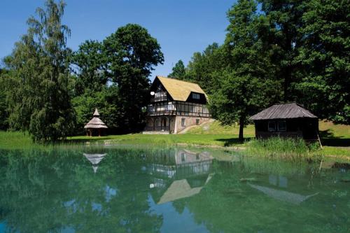 a barn and a house next to a lake at Ośrodek Wypoczynkowy Łańsk in Stawiguda