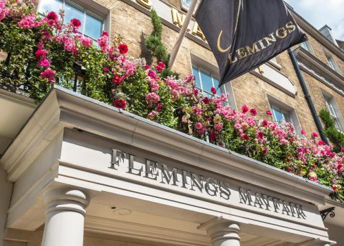 a sign on a building with flowers on it at Flemings Mayfair - Small Luxury Hotel of the World in London