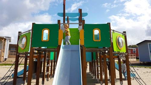Ein kleiner Junge klettert auf einem Spielplatz in der Unterkunft Molecaten Park Noordduinen in Katwijk