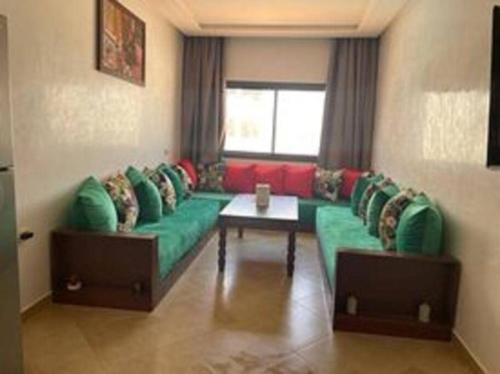 a living room with a green couch and a table at Superbe appartement en bord de mer , banana beach in Aourir