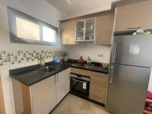 a kitchen with a stainless steel refrigerator and a sink at Superbe appartement en bord de mer , banana beach in Aourir