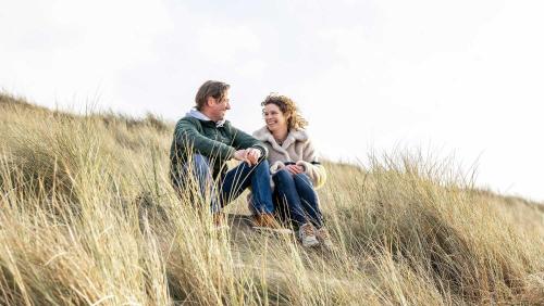 a man and woman sitting in the tall grass at Molecaten Park Noordduinen in Katwijk