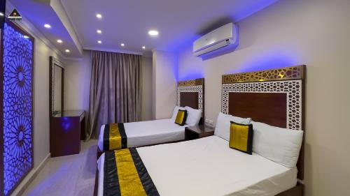 two beds in a hotel room with purple lights at Pyramids Height Hotel & Pyramids Master Scene Rooftop in Cairo