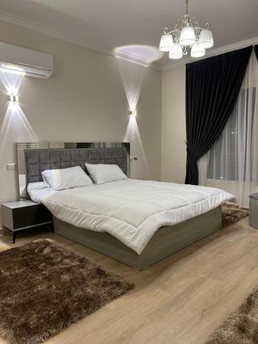a bedroom with a large bed and a chandelier at Elite Residence in Sheikh Zayed