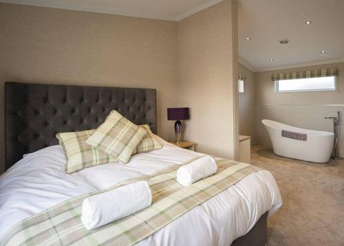 um quarto com uma cama grande e uma banheira em Athelington Hall Farm Lodges em Horham