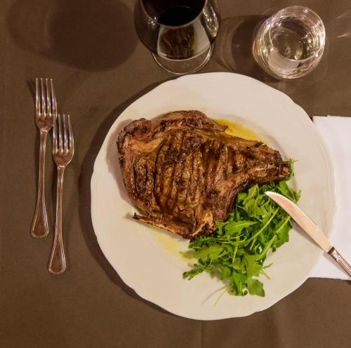 a plate of steak and greens on a table at Tenuta Agricola dell'Uccellina in Talamone