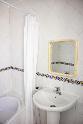 a white bathroom with a sink and a mirror at Casa Clementina in Albufeira