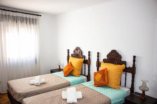 two beds in a room with yellow and orange pillows at Casa Clementina in Albufeira