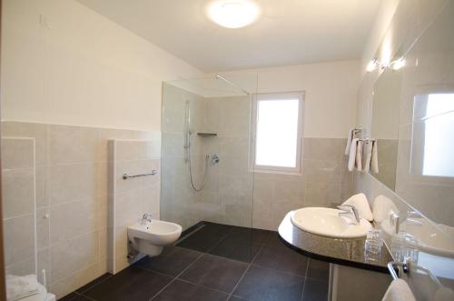 a bathroom with a sink and a toilet and a shower at Garni Hotel Peterlinhof in Caldaro