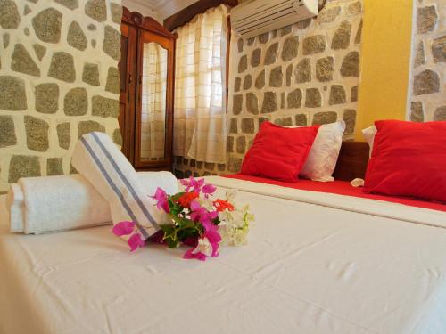 a bed with red pillows and a chair with flowers on it at Chambres d'hôtes Beluga in Nosy Be