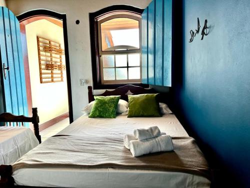a bedroom with a bed with green pillows and a window at Pousada Marques in Paraty