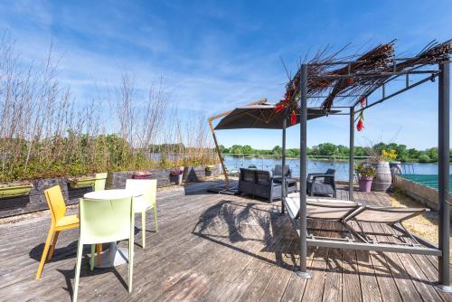 un patio avec une table, des chaises et un parasol dans l'établissement Superbe Appartement Vue sur la Confluence LOIRE, à Bouchemaine