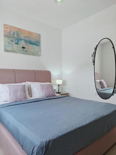 a bed with a blue comforter and a mirror at Alkyonis Apartment Milos in Triovasálos