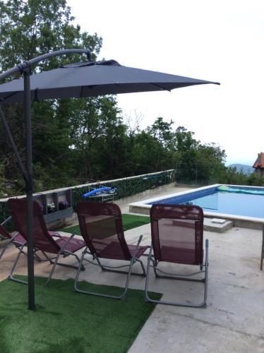 two chairs and an umbrella next to a swimming pool at Lapčiči View in Budva