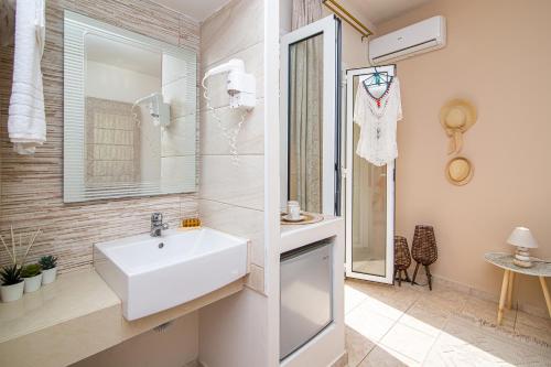 Un baño blanco con lavabo y espejo. en Despina Aparthotel by Philoxenia Hotel & SPA, en Malia