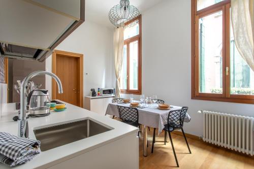 威尼斯的住宿－Rialto Bridge Lovely Apartment，厨房配有水槽和桌椅