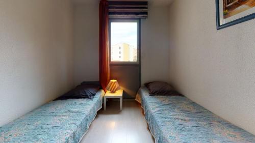 deux lits assis dans une pièce avec une fenêtre dans l'établissement Appartement vue sur le port, proche mer, au Cap d'Agde