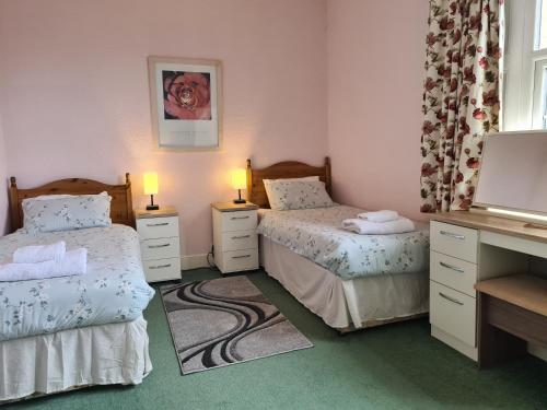 a bedroom with two beds and a desk with two lamps at Church Holiday Apartments in Robin Hood's Bay