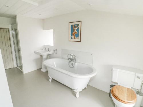 a white bathroom with a tub and a toilet at Langstone Farm in Okehampton