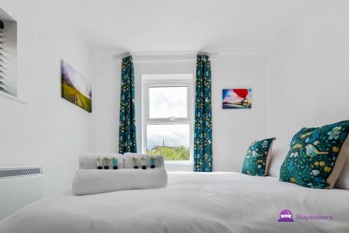 Cama blanca con cortinas azules y ventana en Annie 1 bed Apartment next to rail station - STAYSEEKERS, en Salisbury