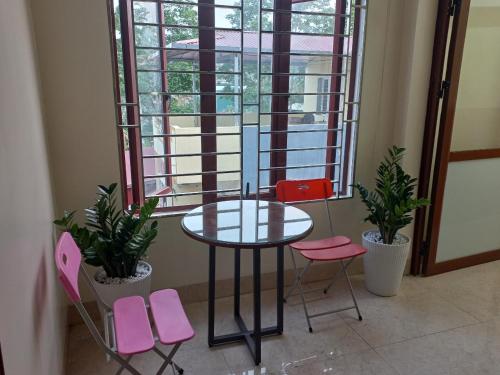 une table et quatre chaises roses devant une fenêtre dans l'établissement Homestay Quyết Thương, à Cao Bằng