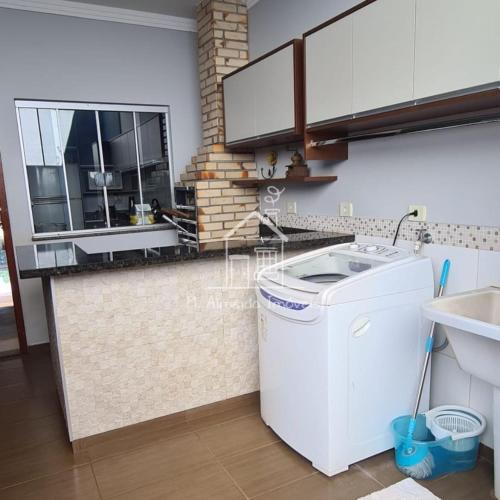 uma cozinha com uma máquina de lavar roupa e um lavatório em Casa Jardim Itália II em Maringá