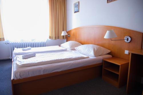 a bed in a hotel room with two pillows at Penzion Diana in Železná Ruda