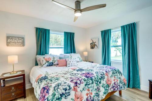 a bedroom with a bed with a floral comforter and blue curtains at Pet-Friendly Cocoa Beach Vacation Rental! in Cocoa Beach