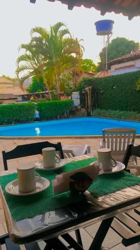 a table with a green table cloth and coffee cups on it at Pousada do Abacateiro in Pirenópolis