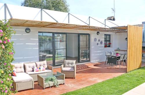 a patio with a couch and chairs and a table at Chalet Isla Papua in Chiclana de la Frontera