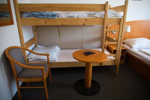 a room with a table and a chair and bunk beds at Penzion Diana in Železná Ruda
