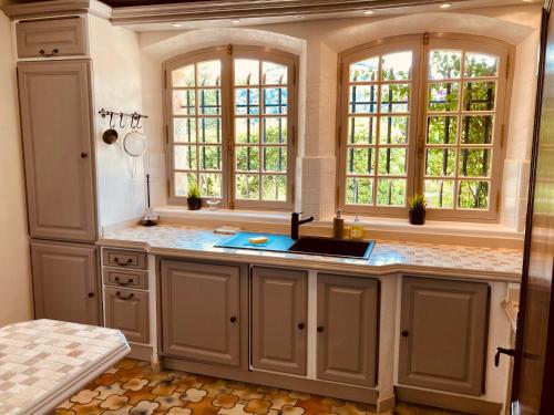 a kitchen with a sink and two windows at Beautiful stone house with fabulous pool and outdoor kitchen in Auribeau-sur-Siagne