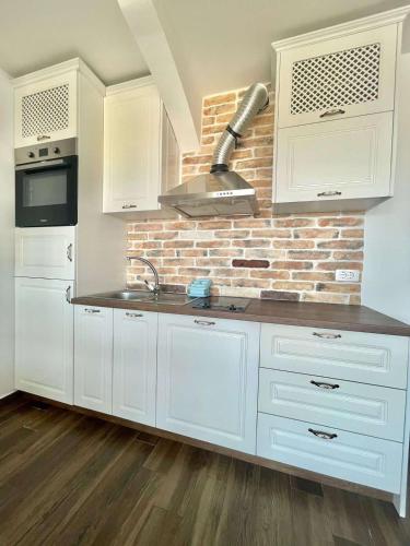 a kitchen with white cabinets and a brick wall at Bucanero Apartments Budva in Budva