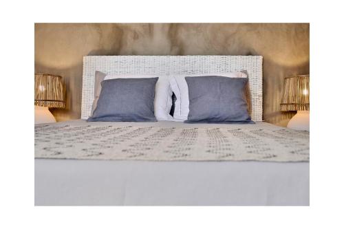 a white bed with blue pillows and a white headboard at Les Jardins de Sitaara in Cucuron