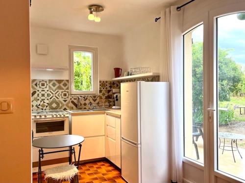 cocina con nevera, mesa y ventana en Gite Harmonie, en Gréoux-les-Bains